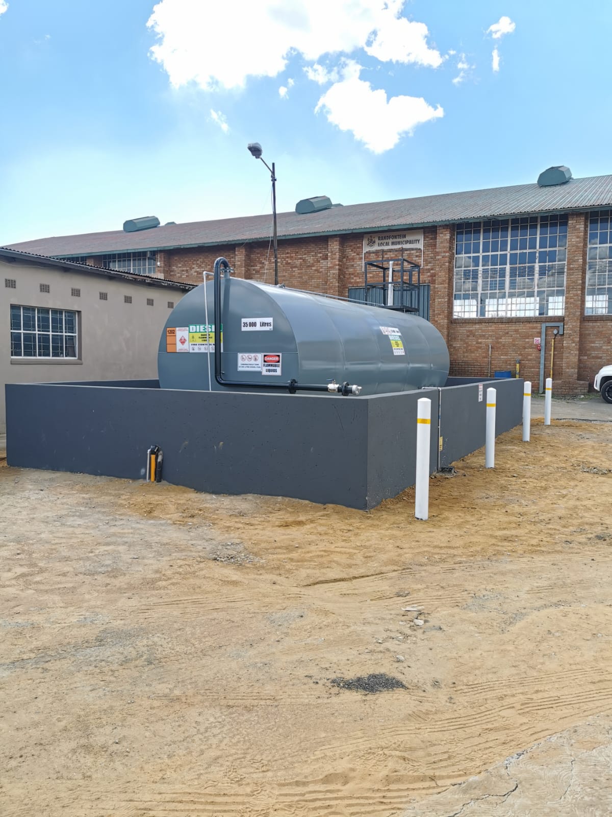 Aboveground diesel storage tank within a bund wall with protective bollards