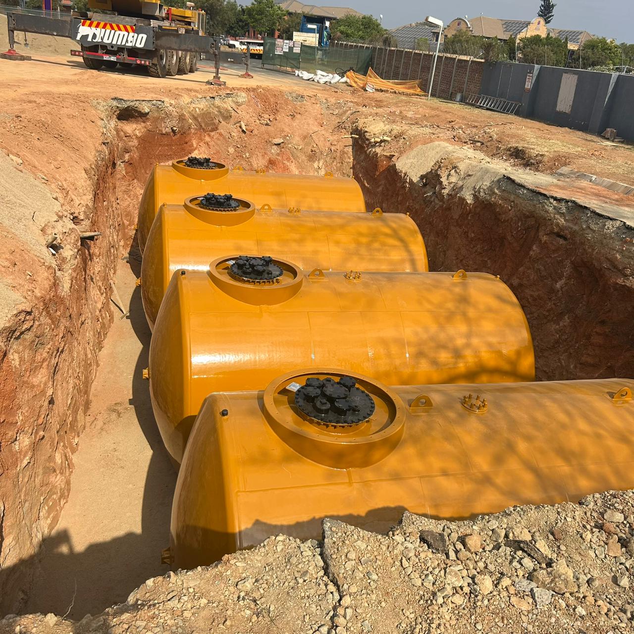 Yellow underground storage tanks positioned in an excavated tank pit